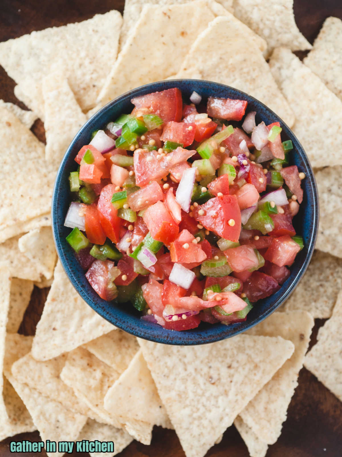 Pico de Gallo without cilantro in a blue bowl on a bed of tortilla chips