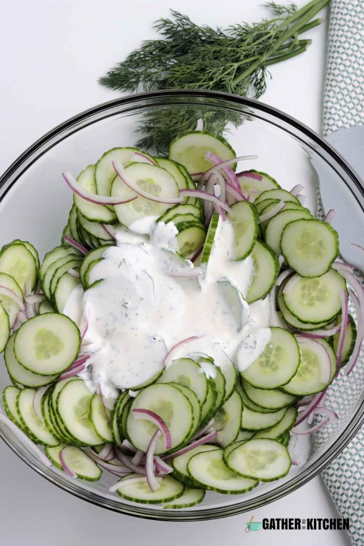 dressing poured over cucumbers and onions in bowl.