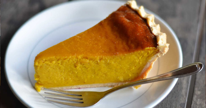 Side view of pumpkin pie slice on a plate.