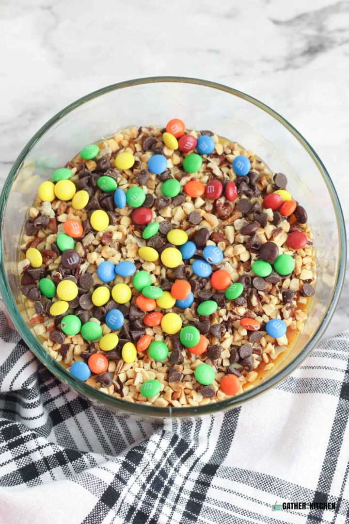 M&M's on top of the nuts & caramel  in a bowl.