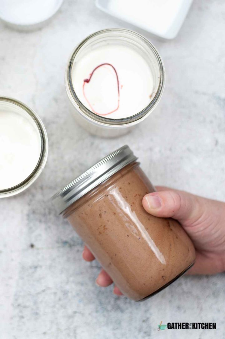 Hand holding the chocolate ice cream in a mason jar.