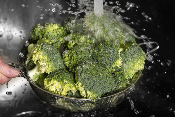 Washing broccoli off under water.