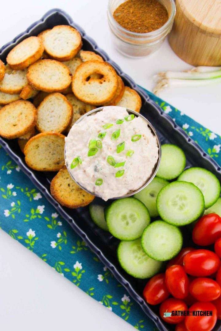 Crab dip surrounded by cucumbers and baguette slices.