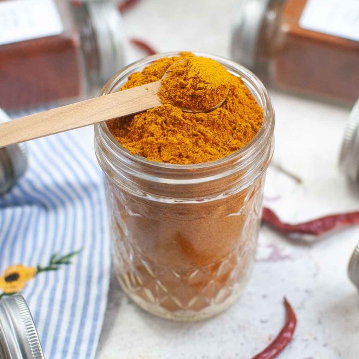 Curry seasoning in mason jar with wooden spoon.