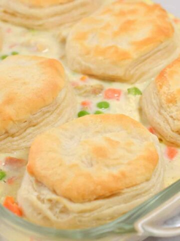 Side view of chicken pot pie casserole with biscuits in baking dish.
