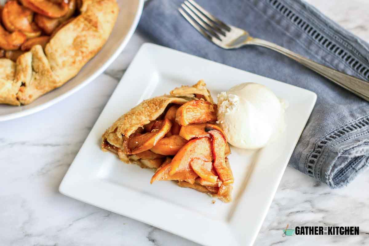 Rustic apple tart on a plate with a scoop of vanilla ice cream.