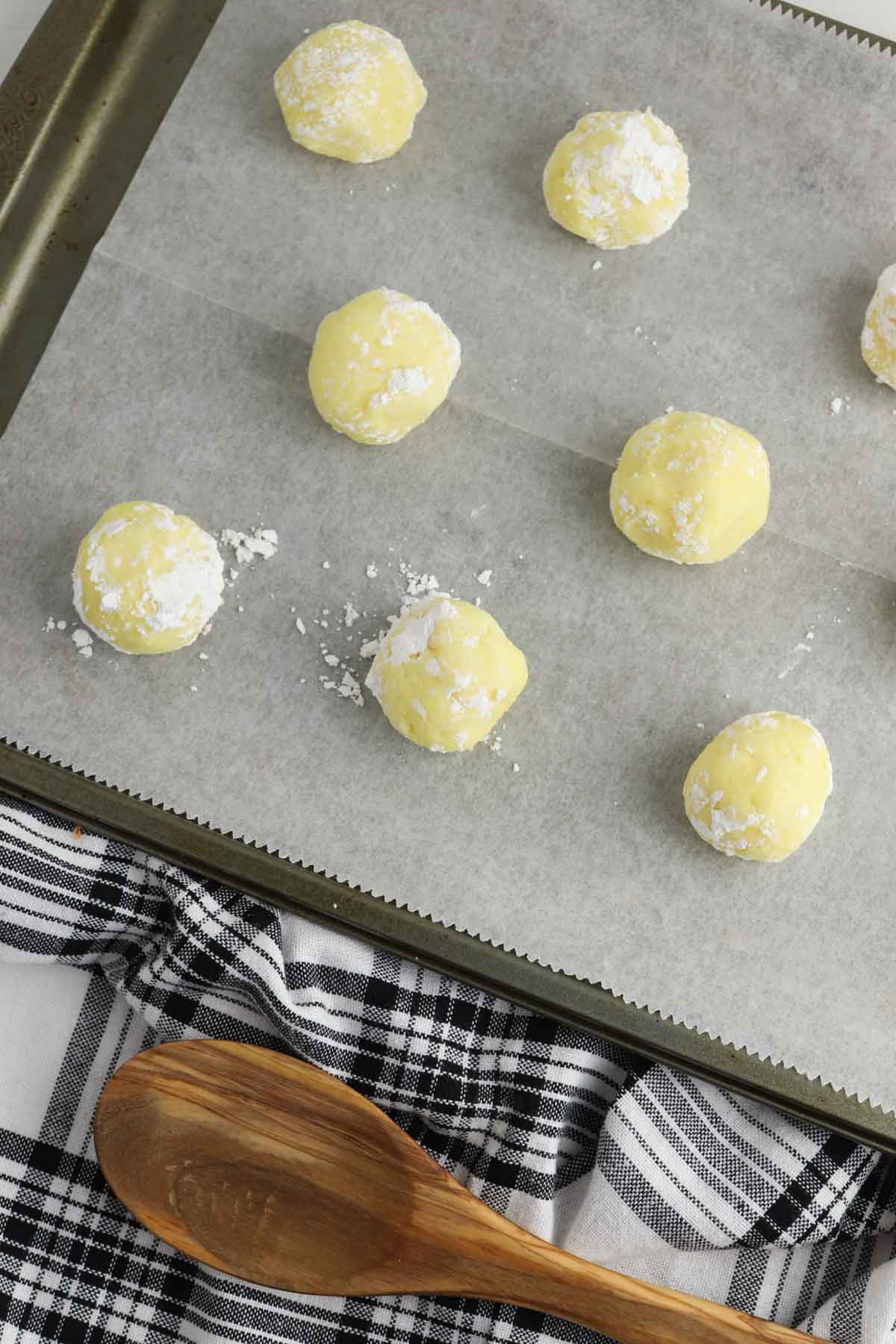 lemon cookie dough balls on cookie sheet.