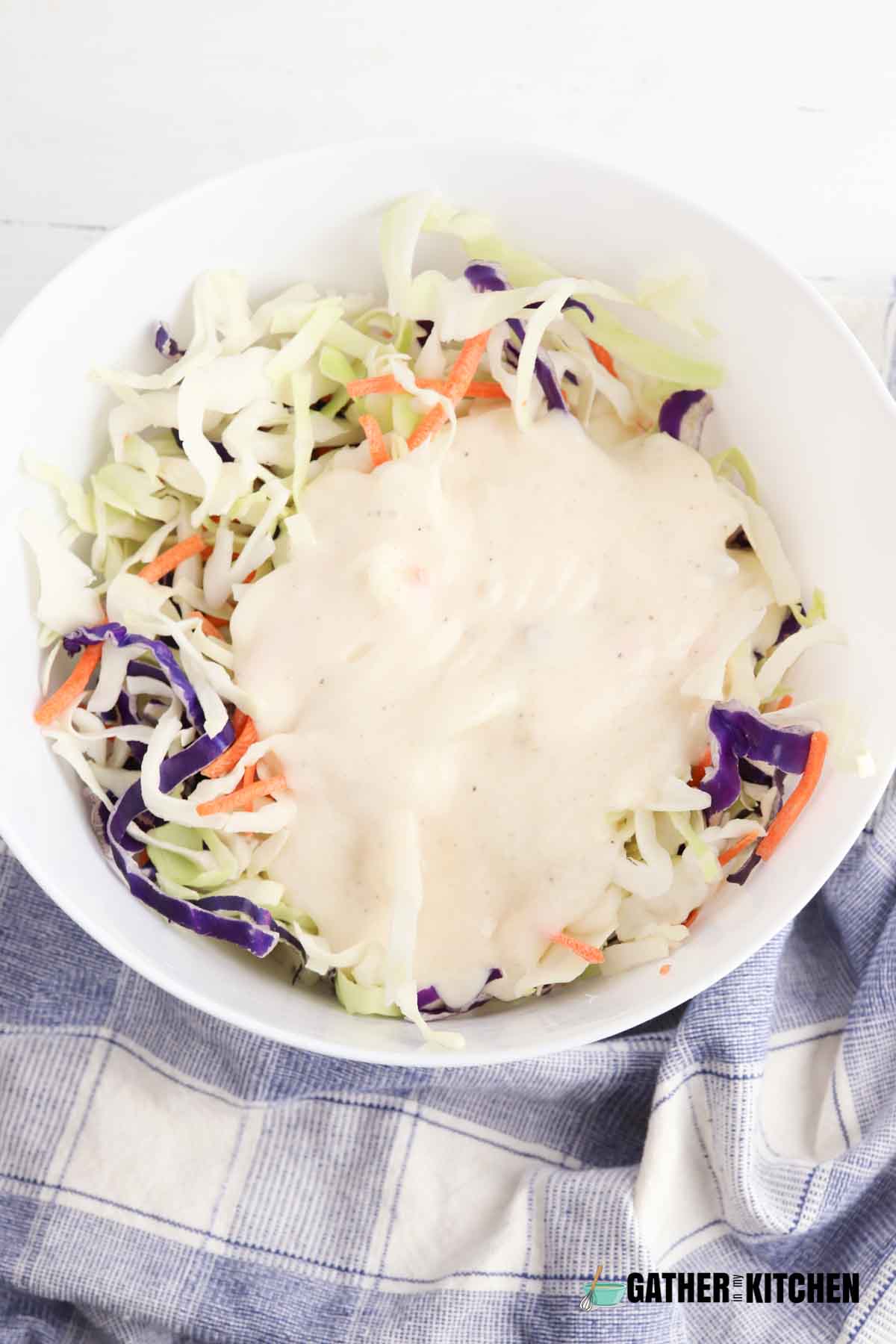 Cole slaw mix topped with coleslaw dressing in bowl.