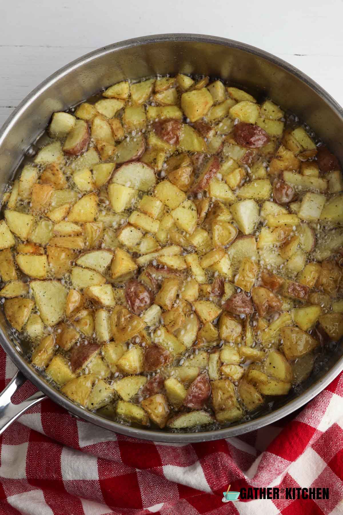 Oil boiling with potatoes and seasoning in it.