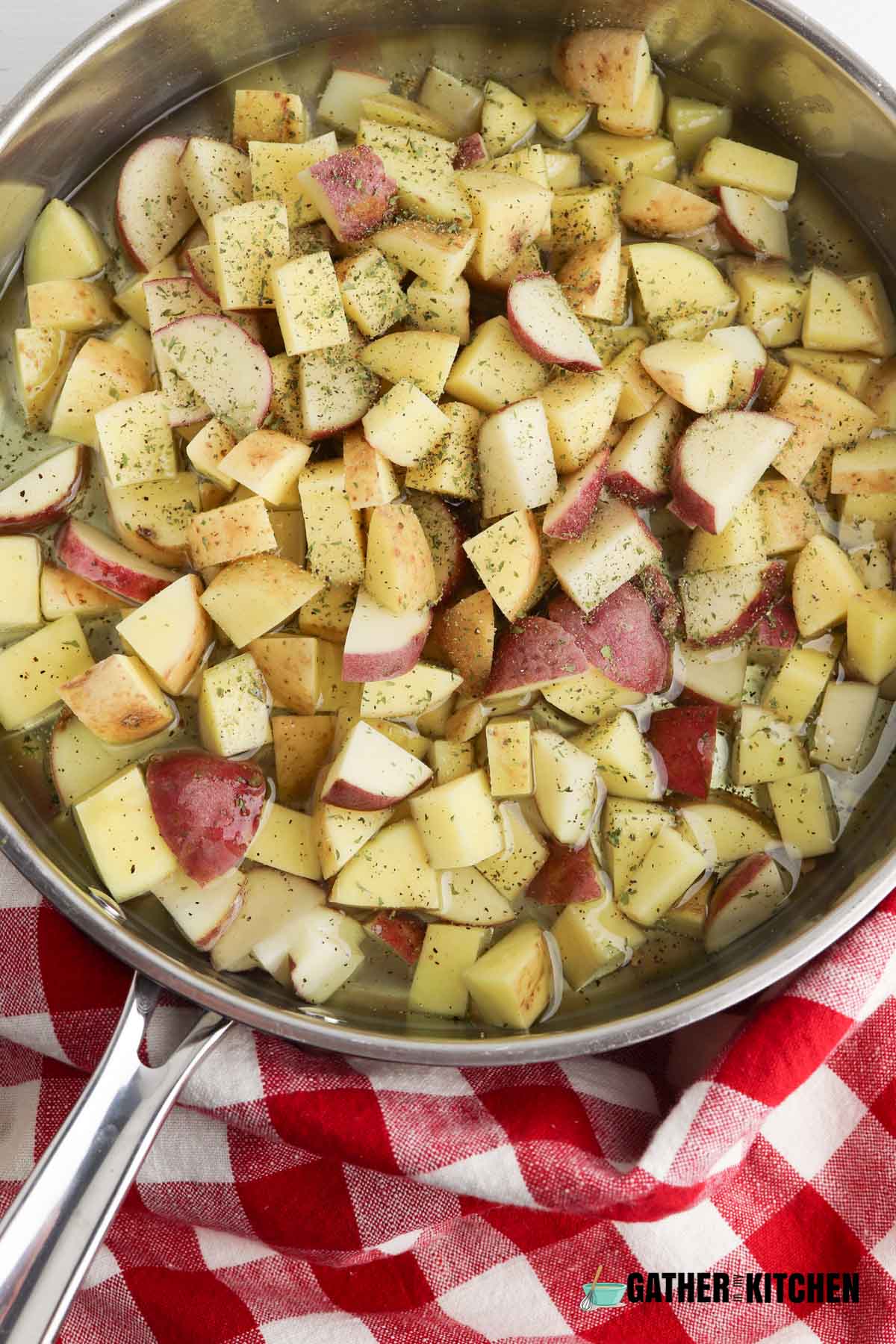Oil, raw potatoes, and seasoning in pan.
