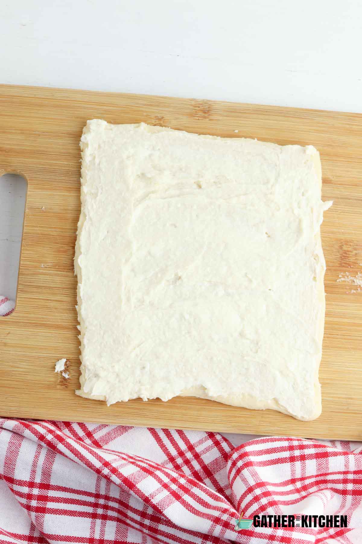 Crescent dough square with cream cheese mixture spread on it.