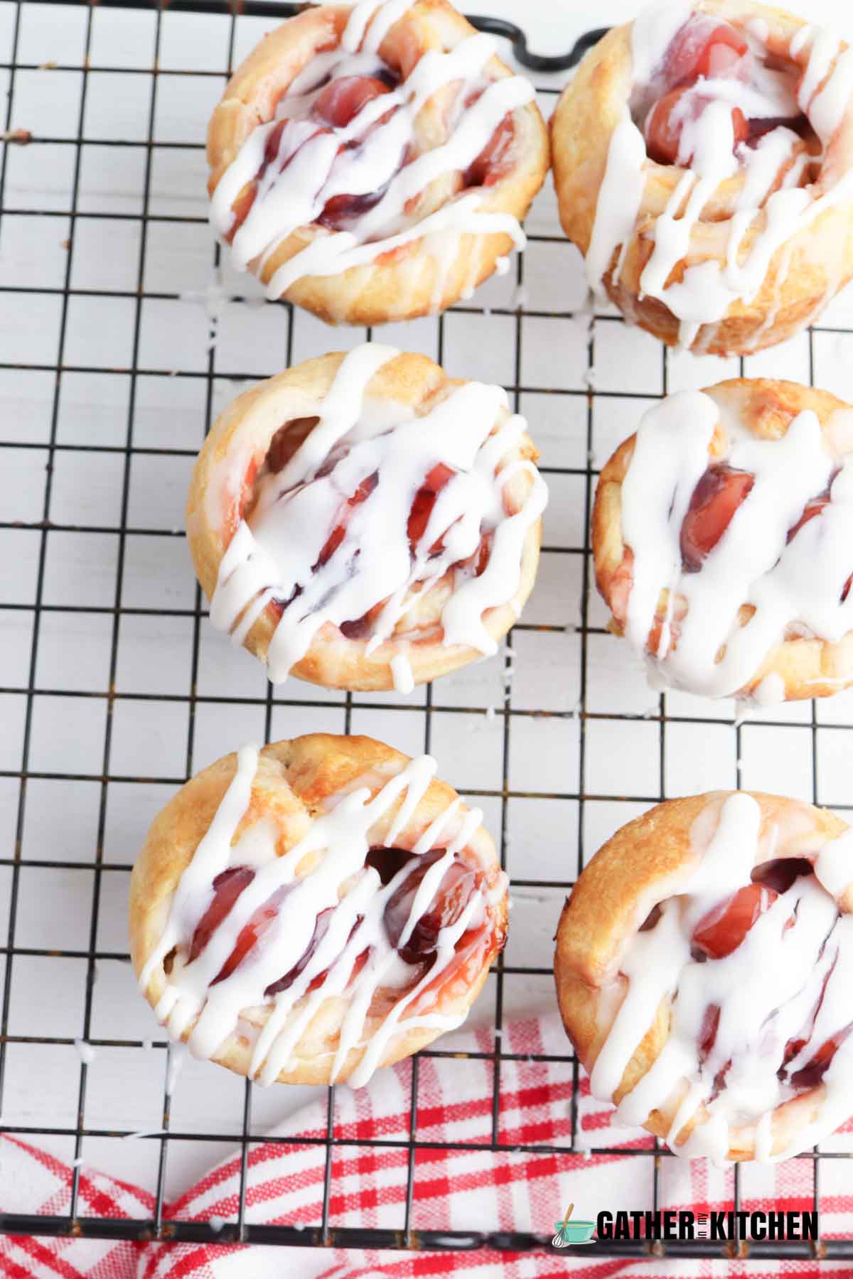 Cherry Danish muffins on wire rack with glaze over the top.