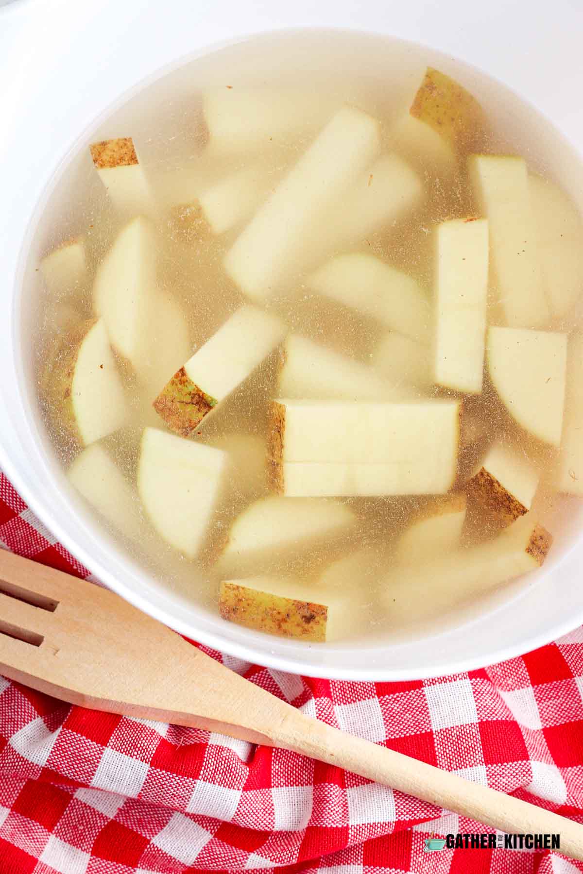 Cut up potatoes in bowl of water.