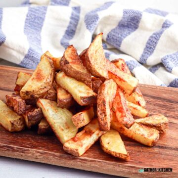 Air fryer potato wedges in a pile on a cutting board.