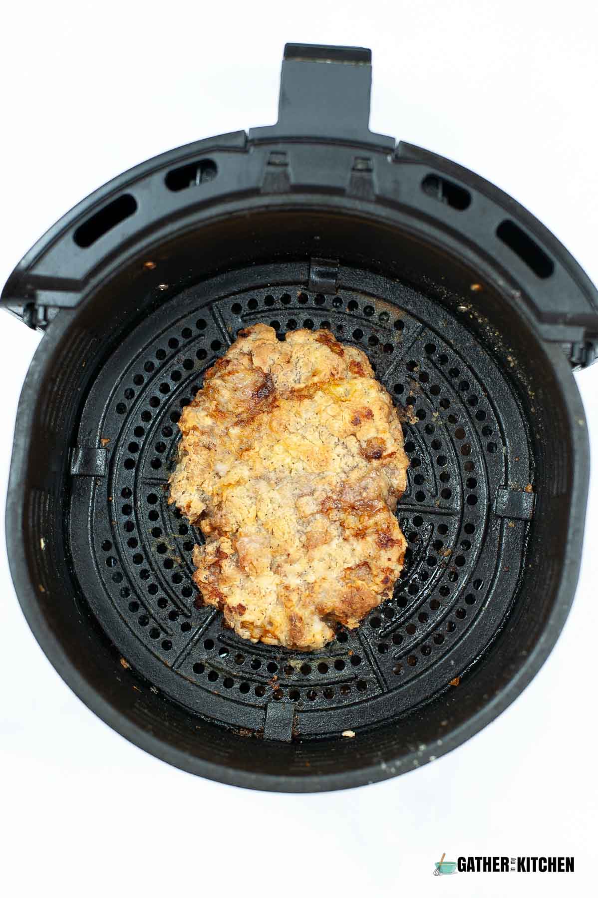 Cooked chicken fried steak in an air fryer basket.