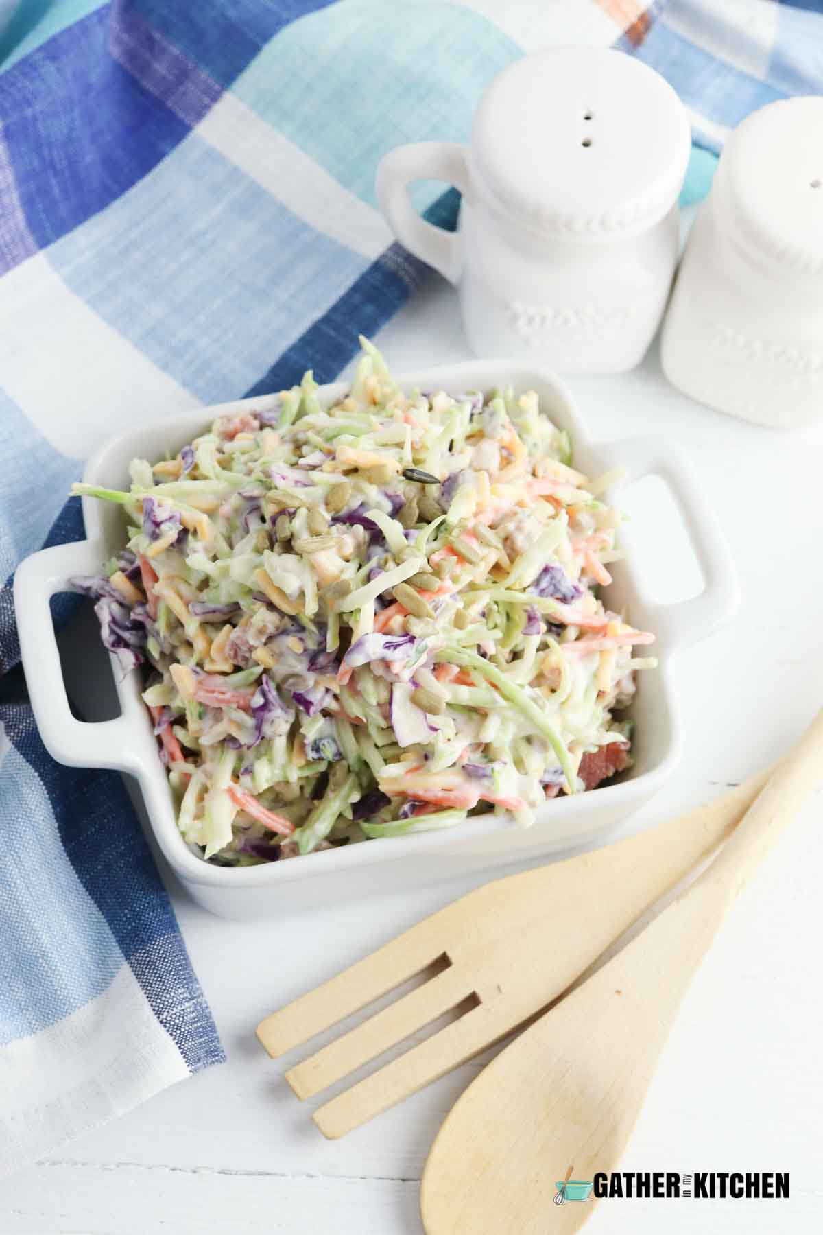 Top down view of broccoli slaw in a square white bowl.