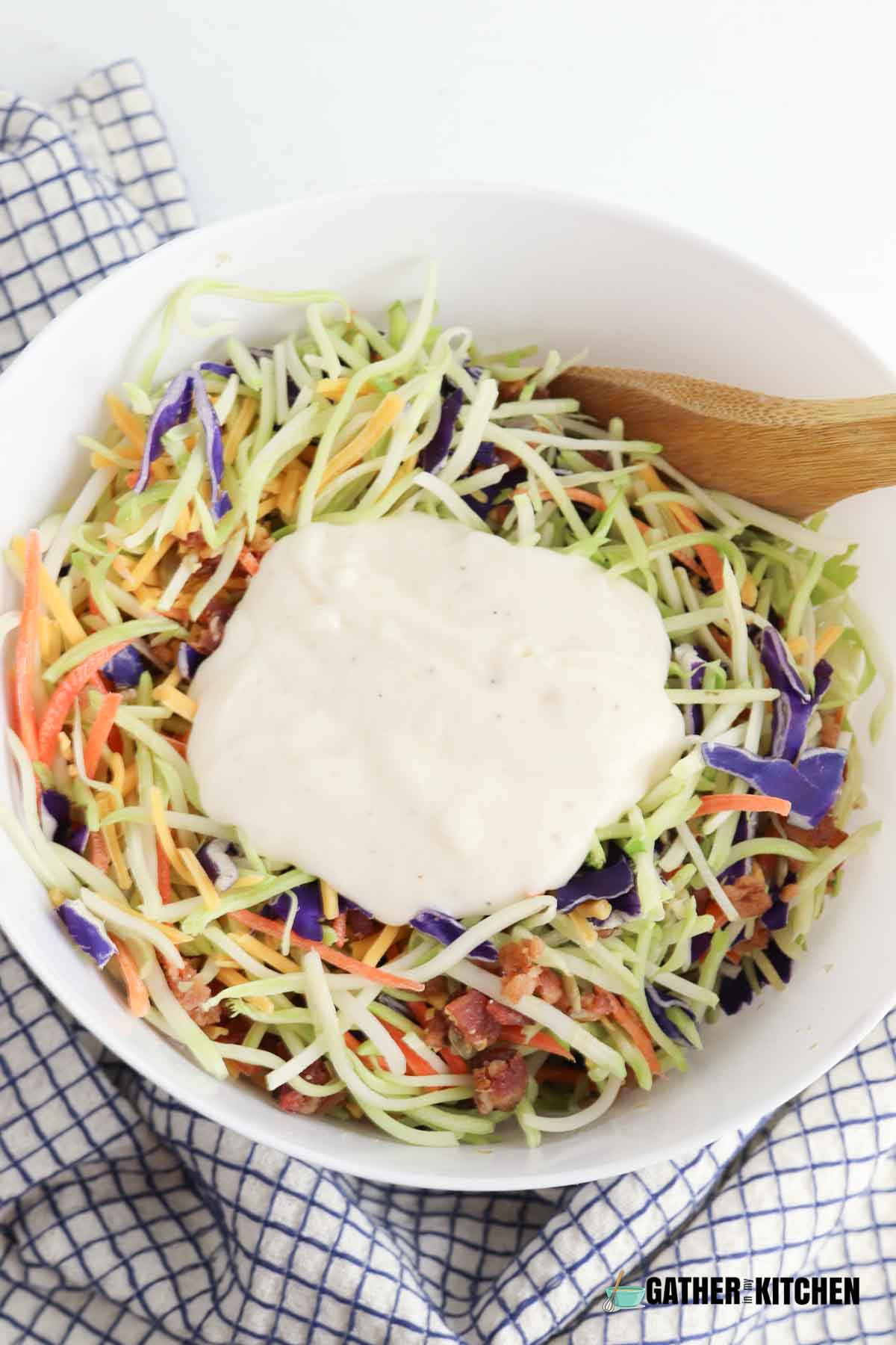 Broccoli slaw ingredients combined together with the dressing on top of them.