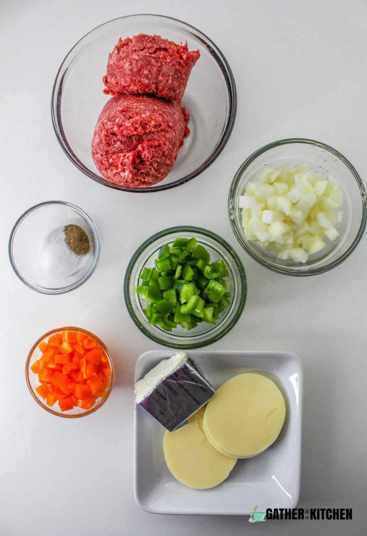 Ingredients for Philly Cheesesteak casserole: ground beef, chopped onions, chopped bell peppers, chopped orange bell pepper, provolone cheese, cream cheese, and salt & pepper.