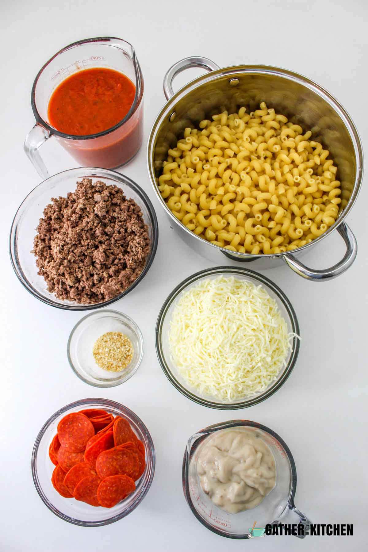 Ingredients for pizza casserole: elbow macaroni, ground beef, onions, cream of mushroom, mozzarella, minced onions, and pizza sauce.