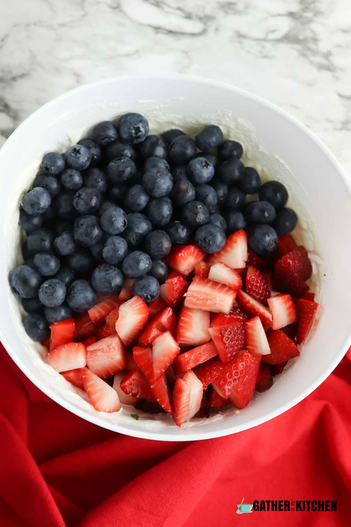Bowl of cream cheese mixture and strawberries and blueberries on top.