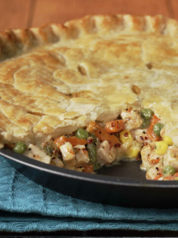 Chicken pot pie in a pie dish with a slice taken out.