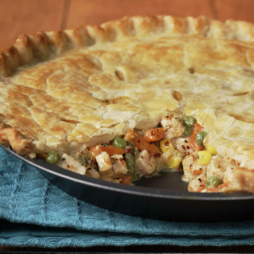 Chicken pot pie in a pie dish with a slice taken out.