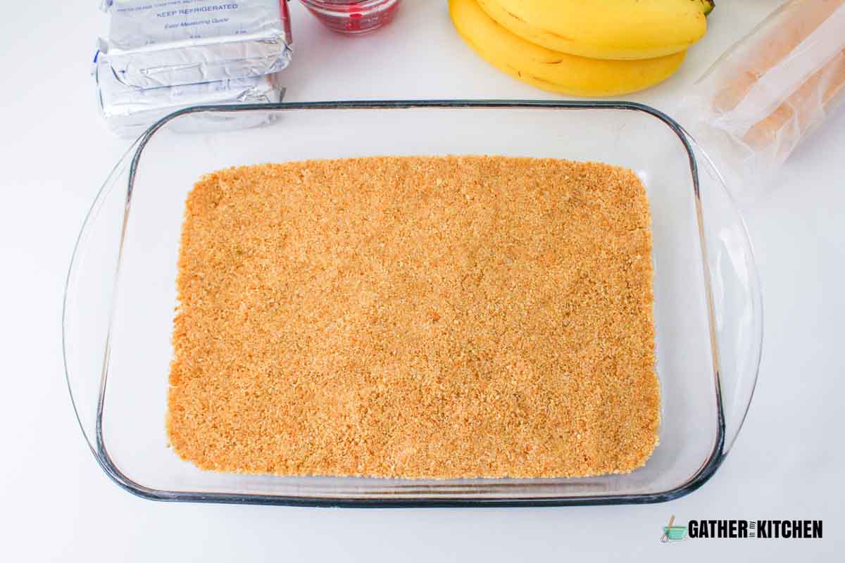 Graham cracker mixture pressed to the bottom of a 9x13 glass pan.