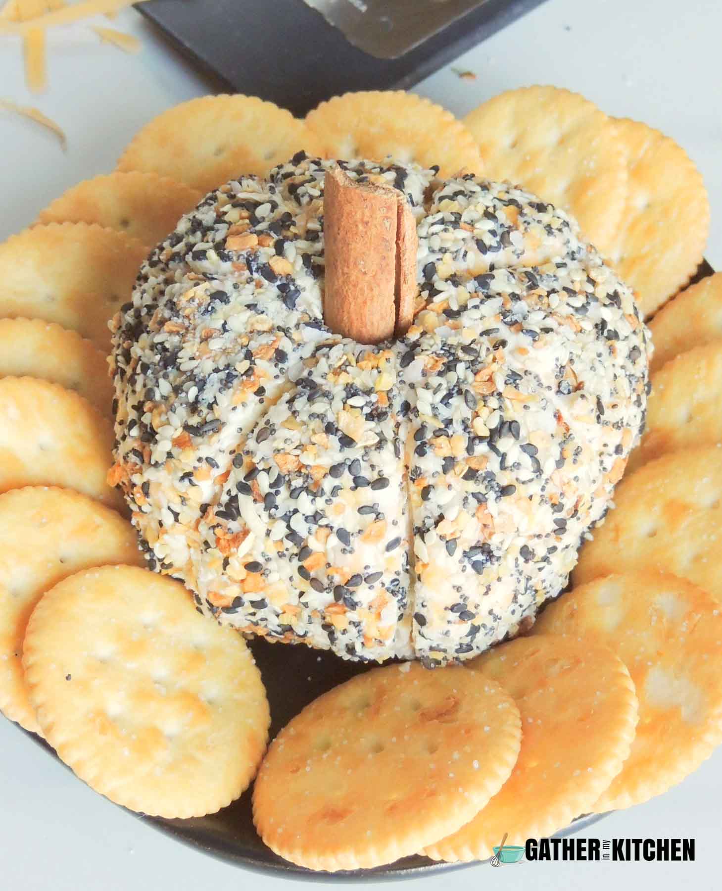 Closeup of pumpkin cheese ball on a plate with Ritz crackers around it.