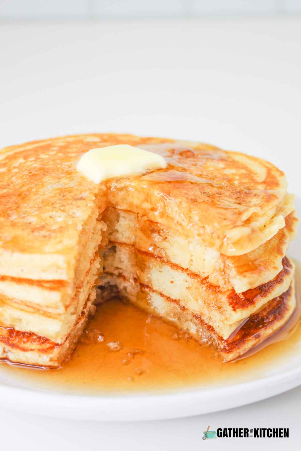 A closeup of a stack of buttermilk pancakes swimming in syrup.