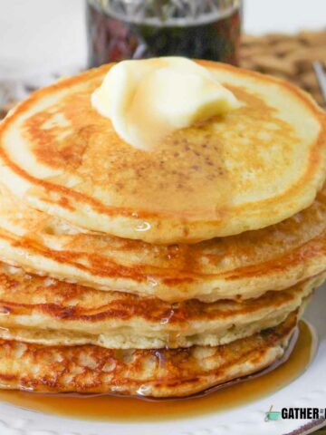 A pile of buttermilk pancakes with butter on top.