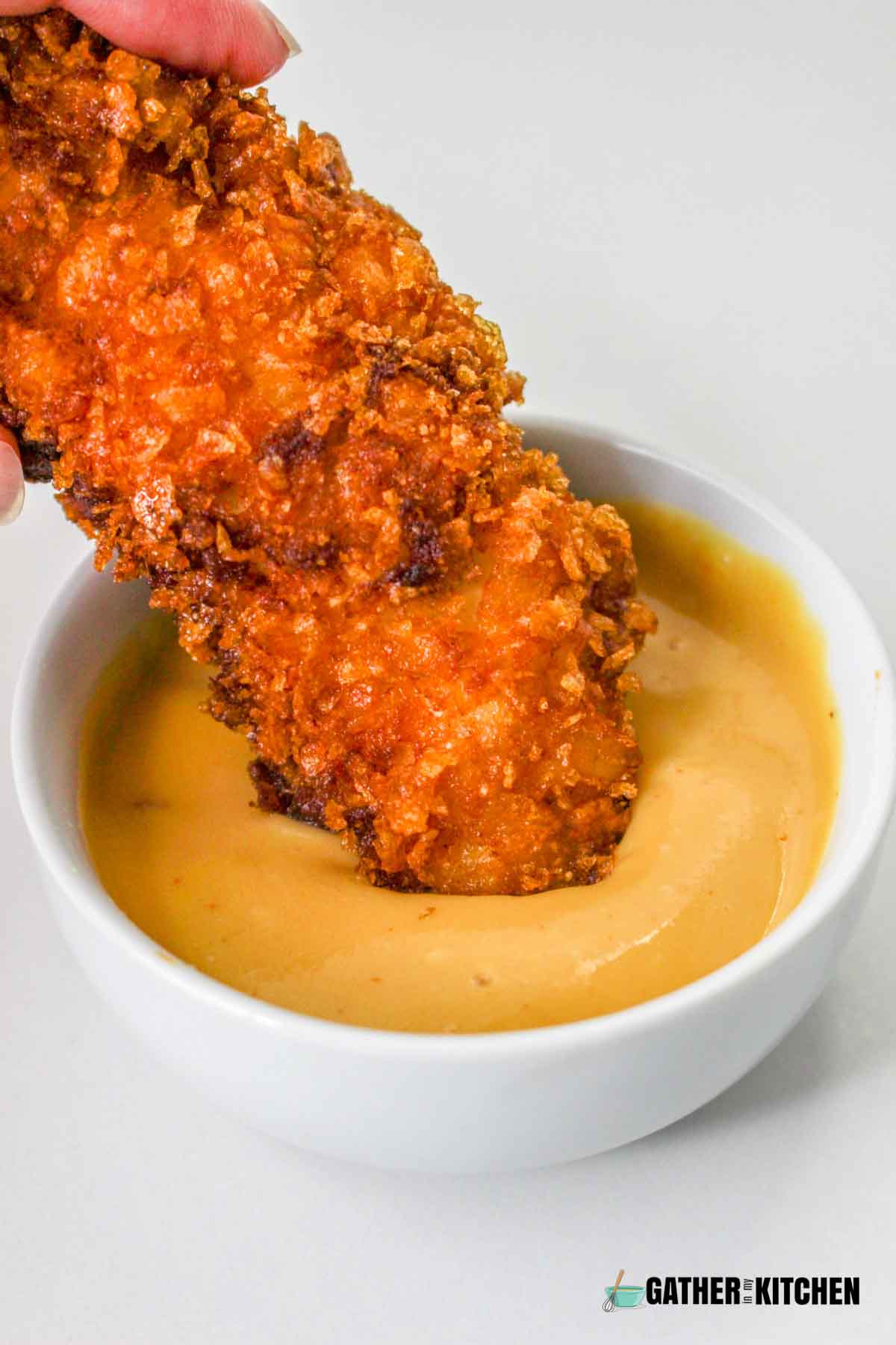 Cornflake fried chicken dip in a sauce.