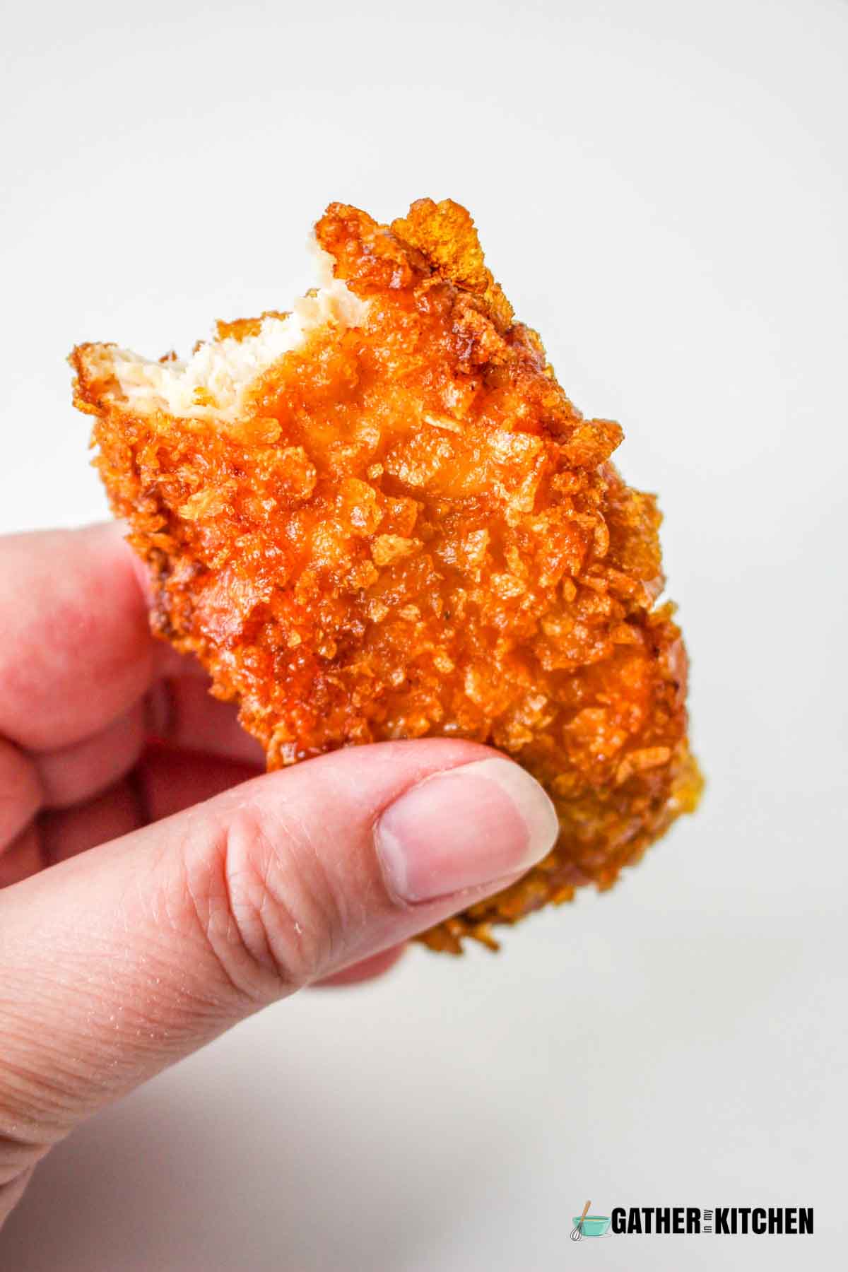 Holding a bite of cornflake fried chicken.