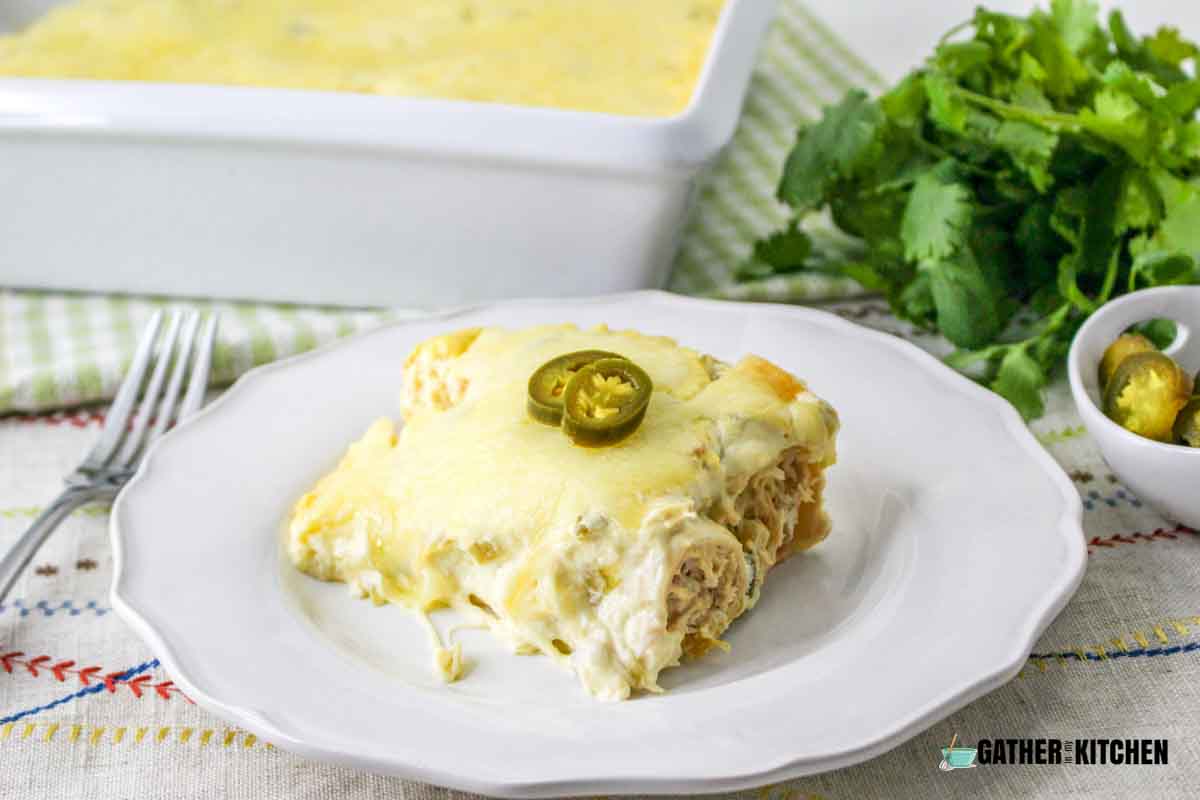 A square slice of creamy chicken enchilada with jalapeno slices on top.