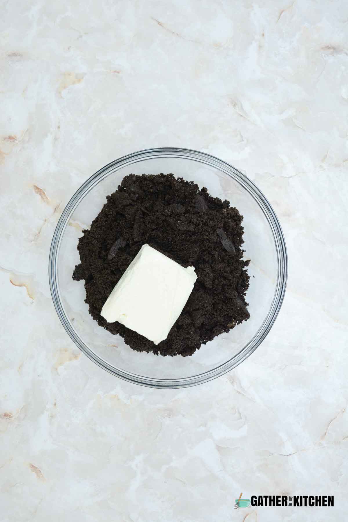 Crushed oreos and cream cheese in a bowl.