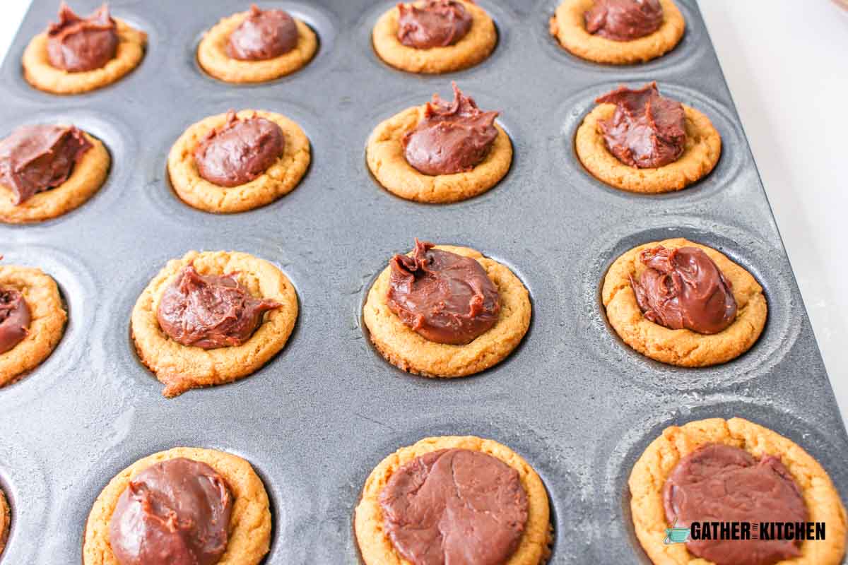 A baking sheet of cookies filled with a dollop of fudge in the center.