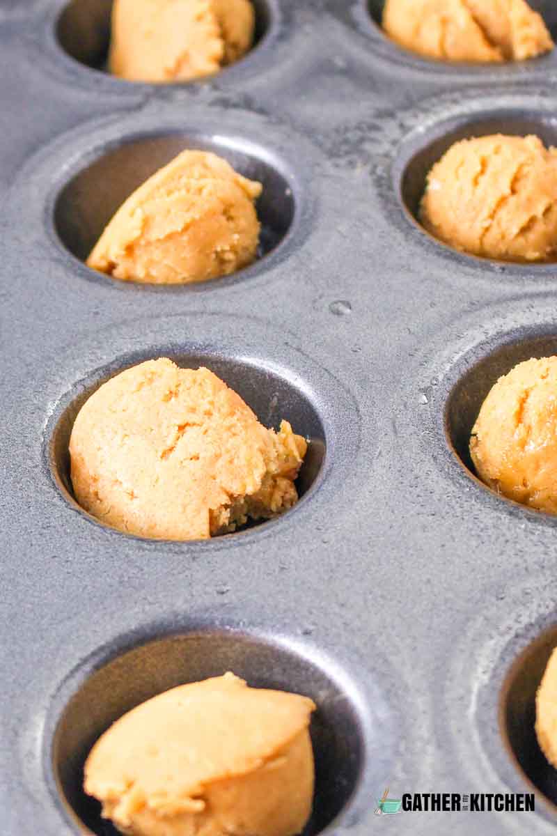 A mini-muffin baking sheet filled with cookie dough.