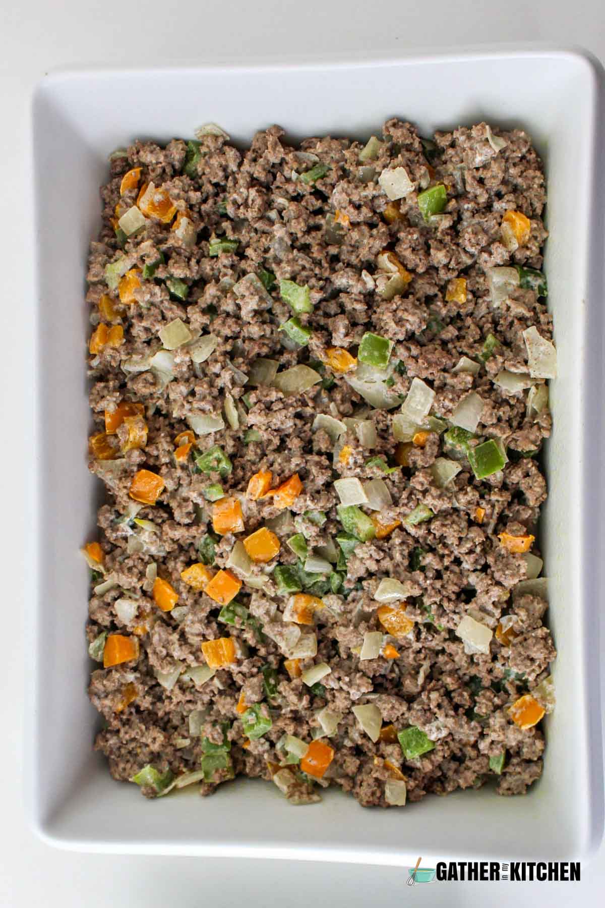 An even layer of beef and veggie mix in a casserole dish.