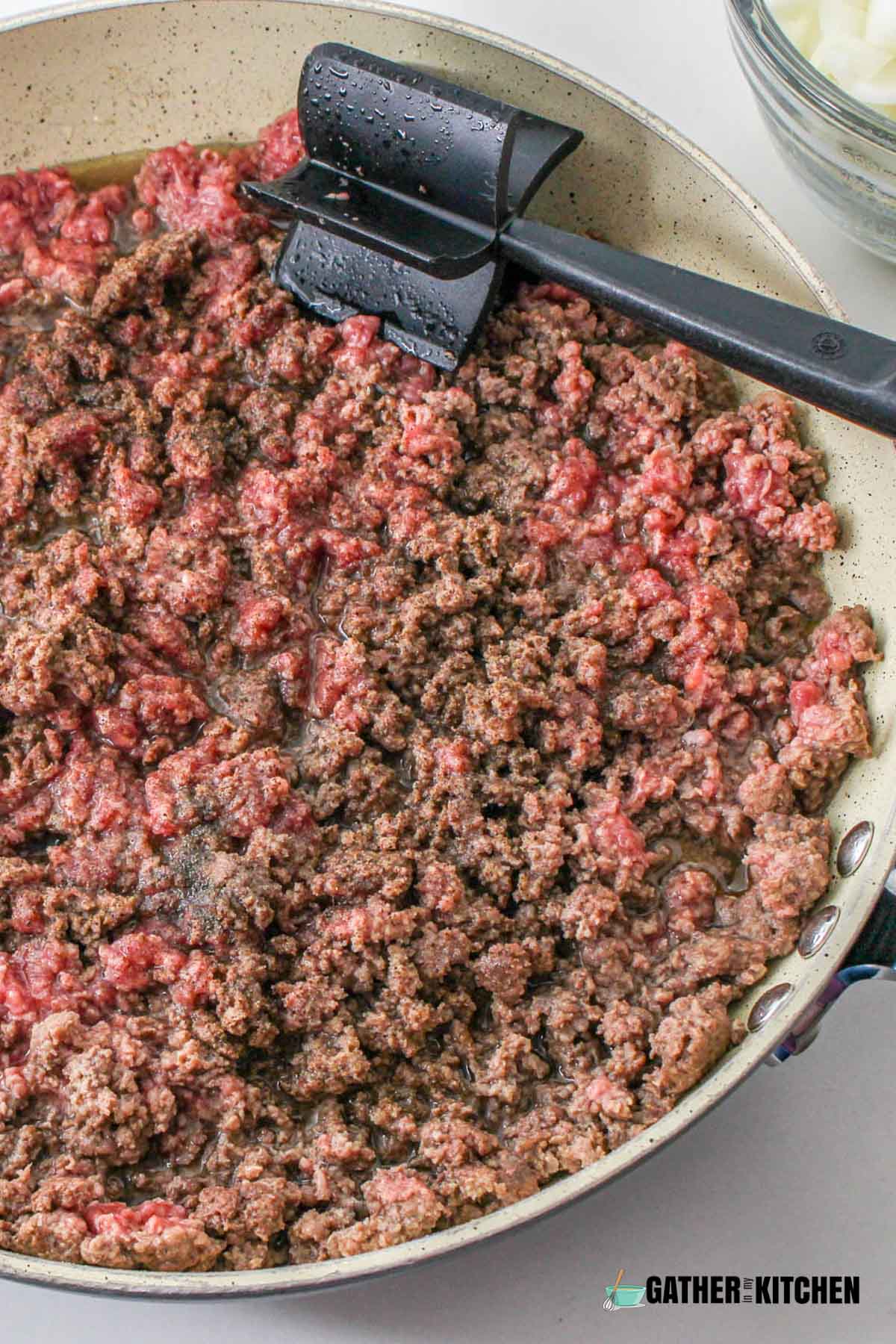 Lean ground beef on skillet with a spatula over it.
