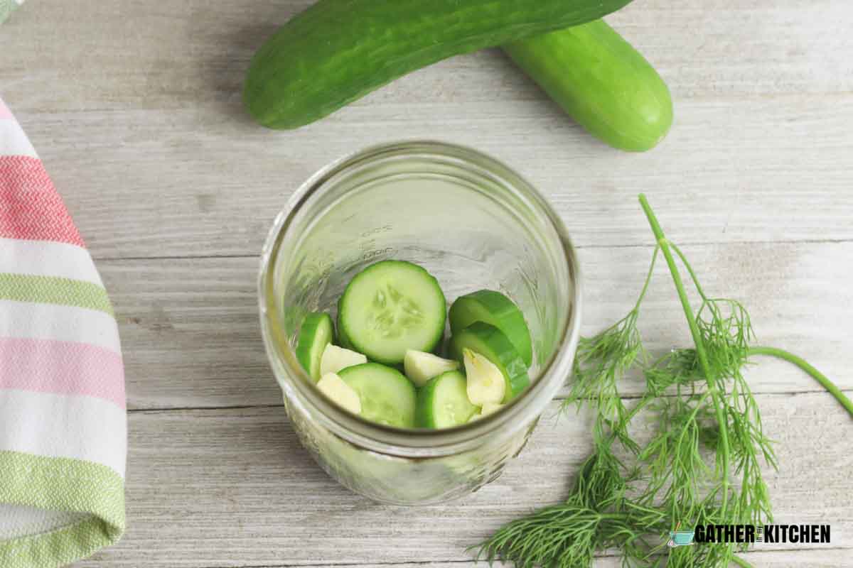 A jar filled with sliced cucumbers and garlic.