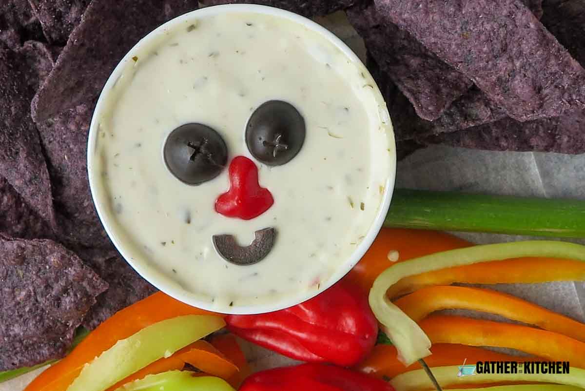 A closeup of the veggie dip with olives and pepper to recreate a face.