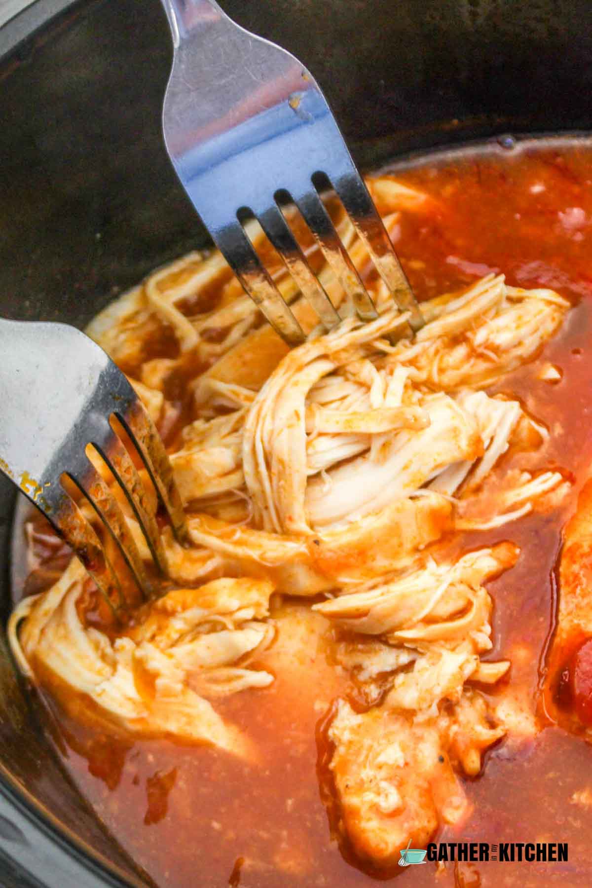Forks pulling apart chicken into shreds.