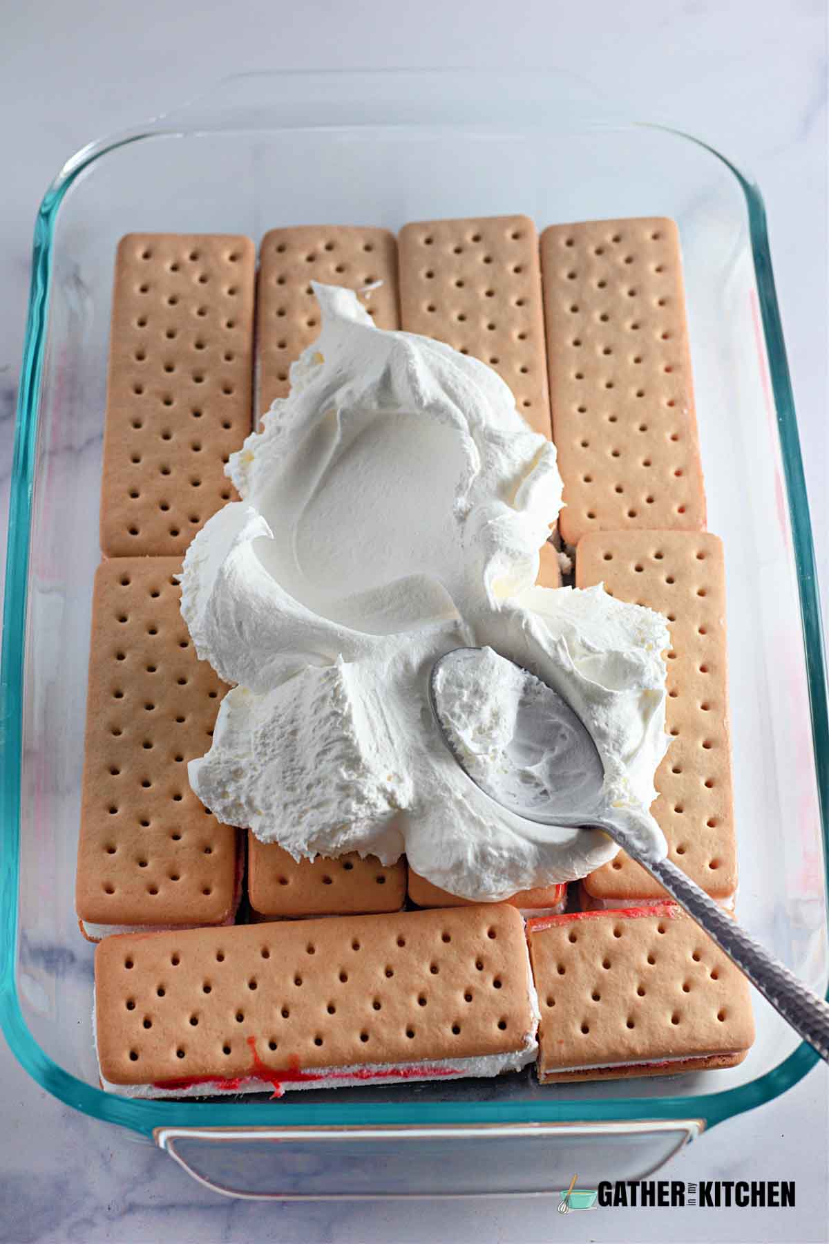 A tray with a layer of ice cream sandwiches with cool whip on top.