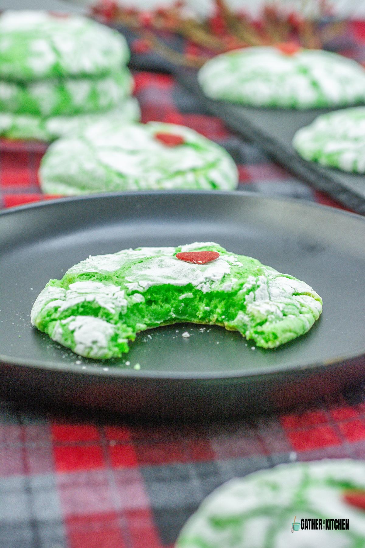 A Grinch cookie on a plate with a bite off it.