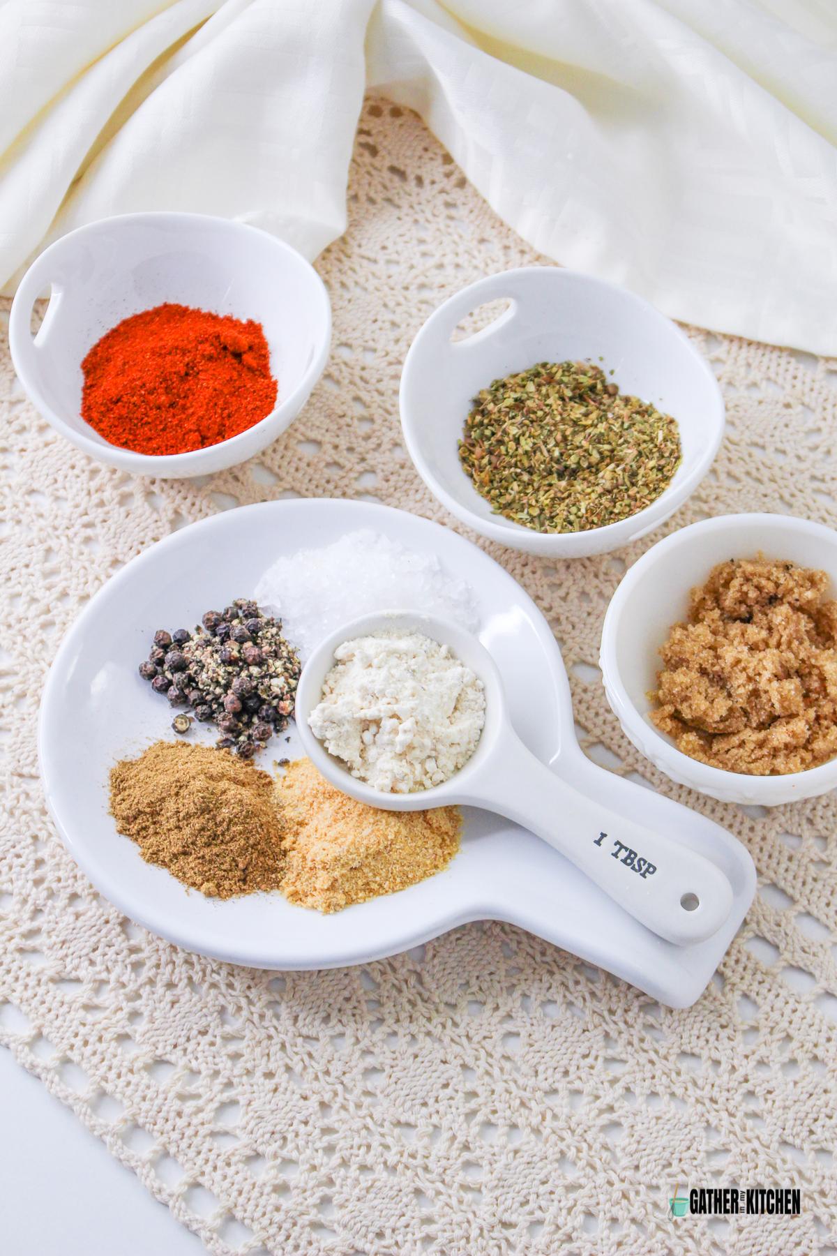 Bowls of ingredients: kosher salt, paprika, onion powder, garlic powder, dried oregano, black pepper, light brown sugar, and cumin.
