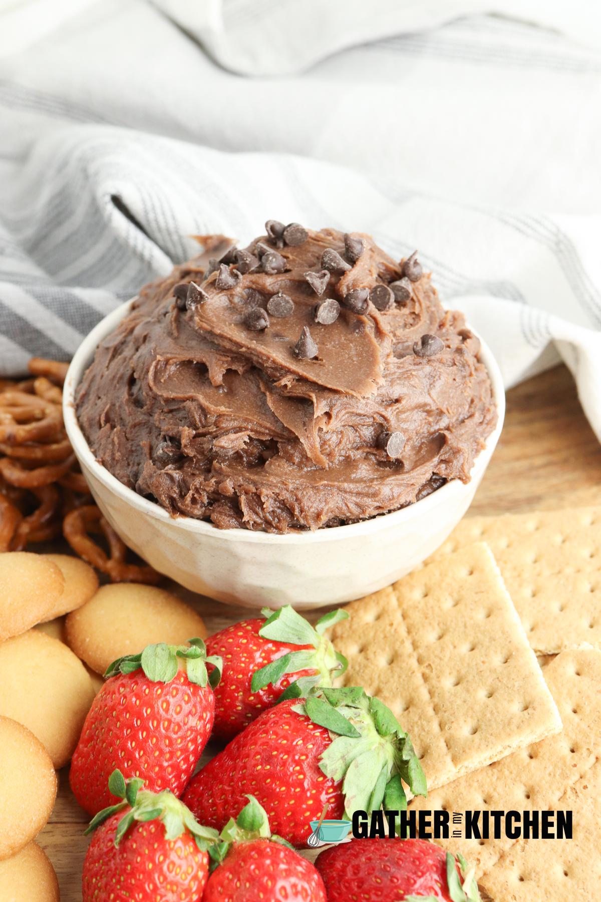 A bowl of brownie batter dip with strawberries, crackers and pretzels.