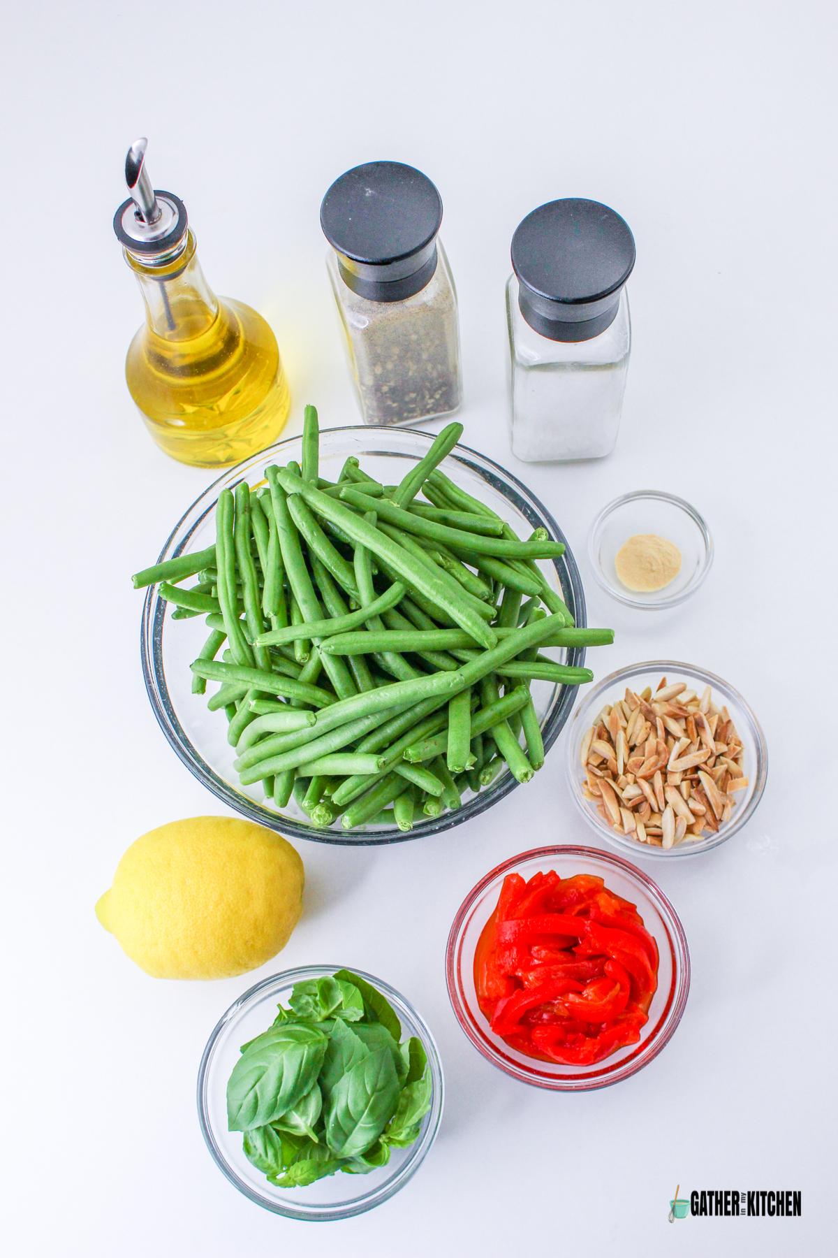 Ingredients: olive oil, pepper, salt, green beans, garlic powder, slivered almonds, bell peppers, fresh basil leaves, and a lemon.
