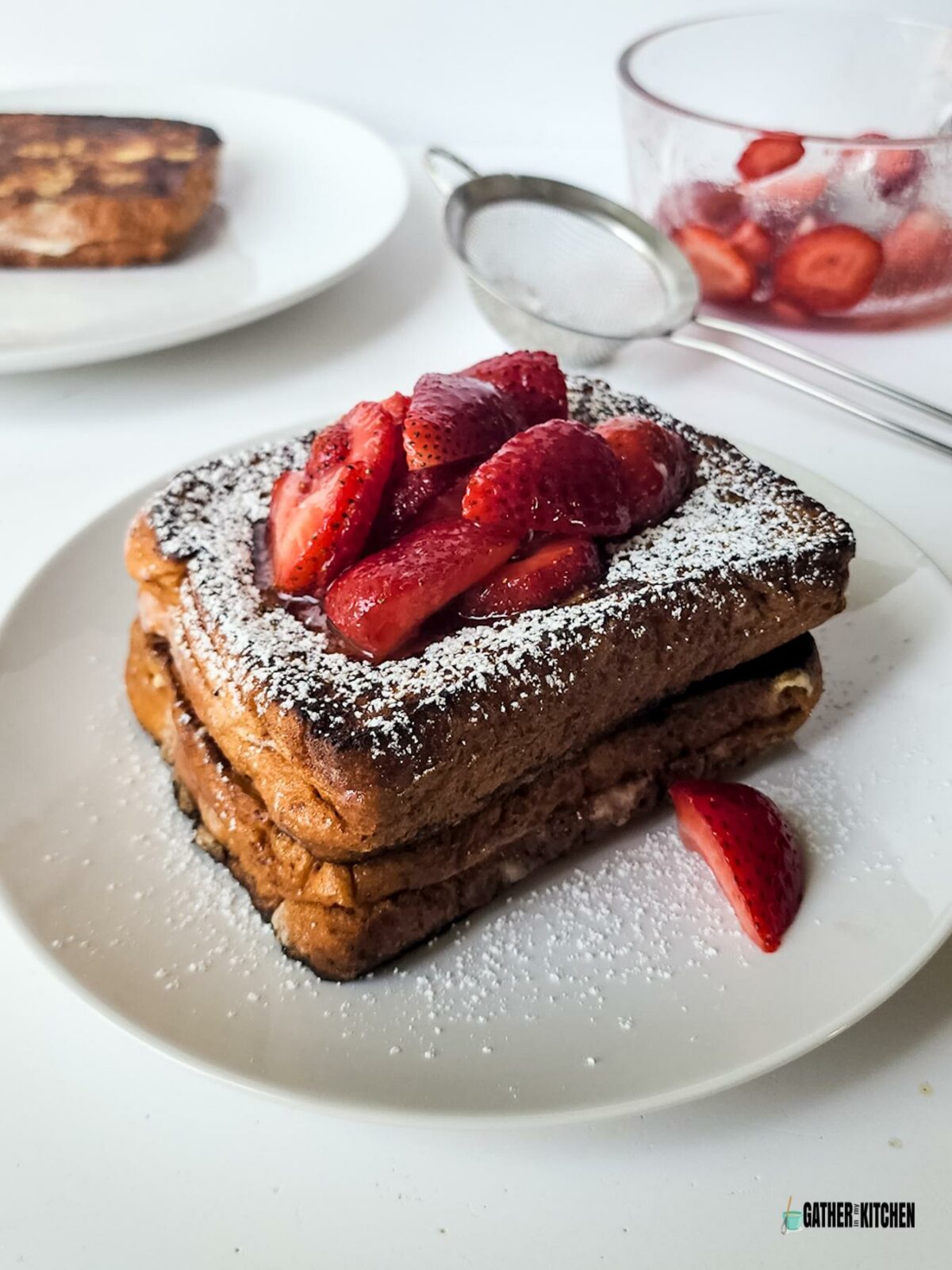 French toast with powdered sugar and strawberries on top.