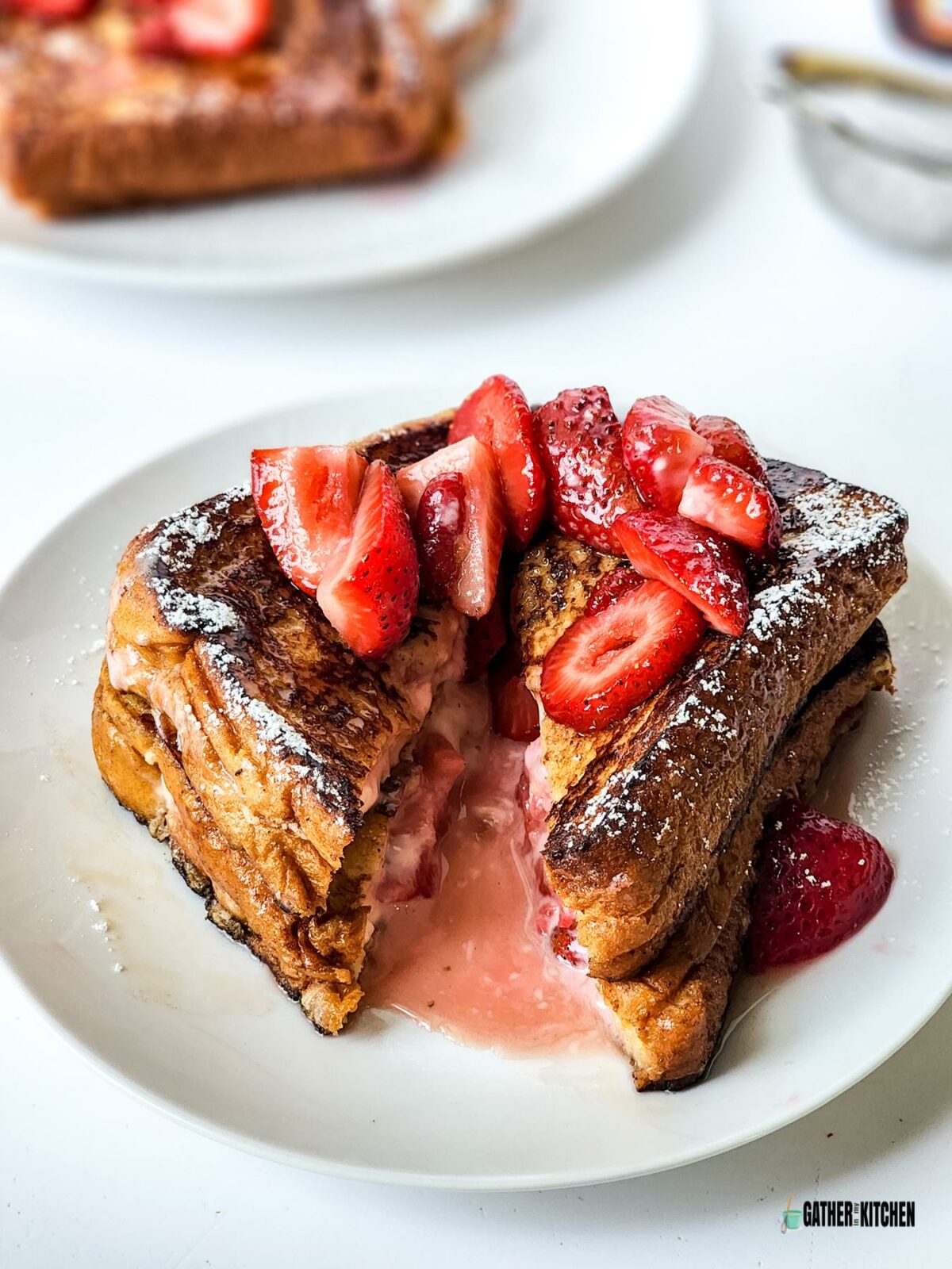 A plate of Strawberry Cheesecake French Toast with a slice taken out in the middle.