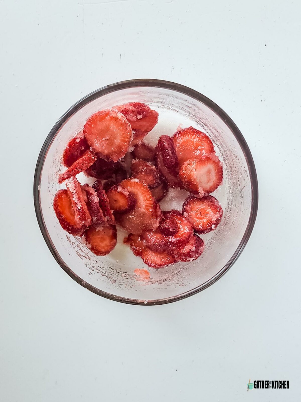 Strawberries and sugar mixed in a bowl.