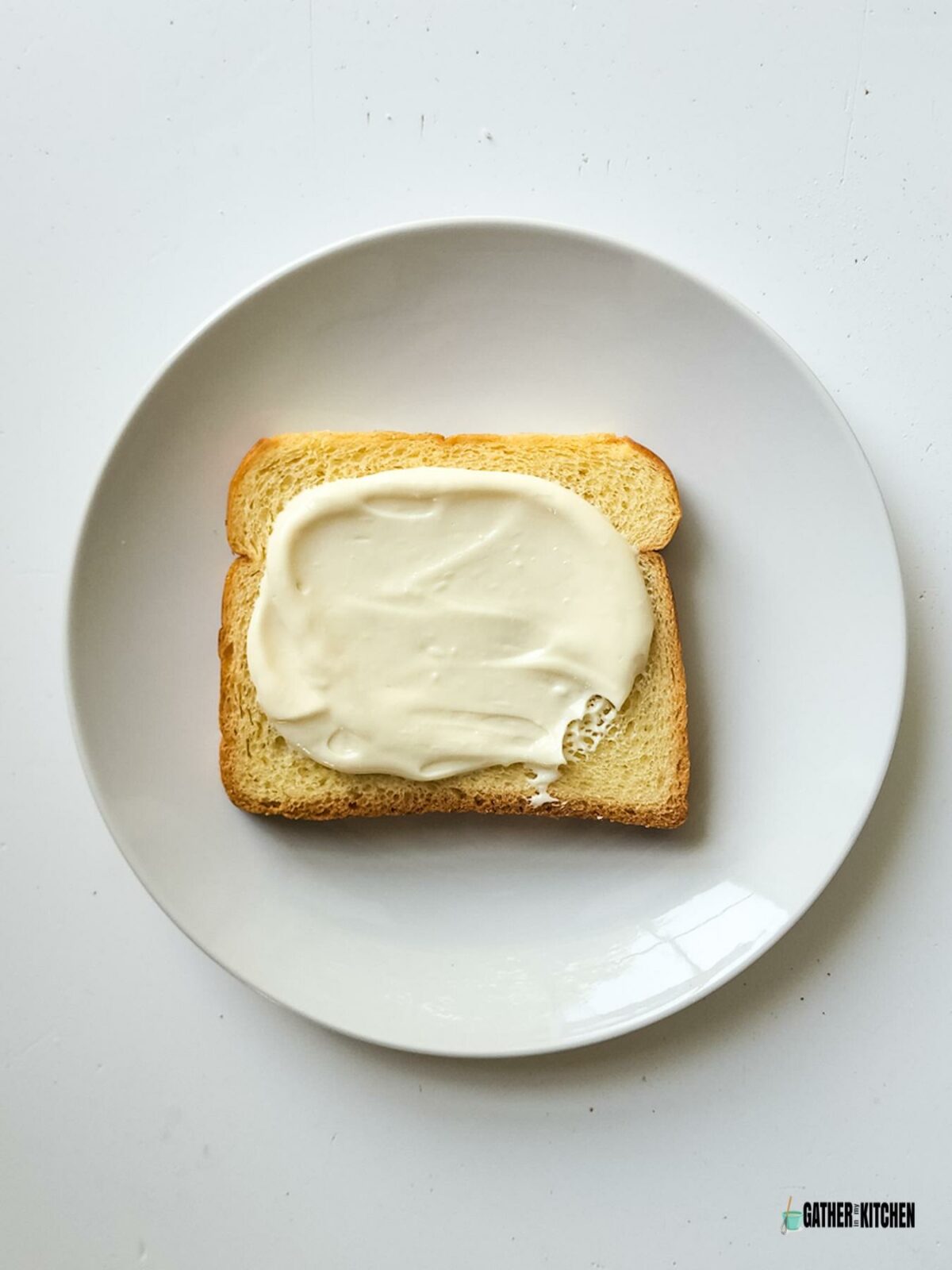 A piece of bread with cream cheese spread on it.